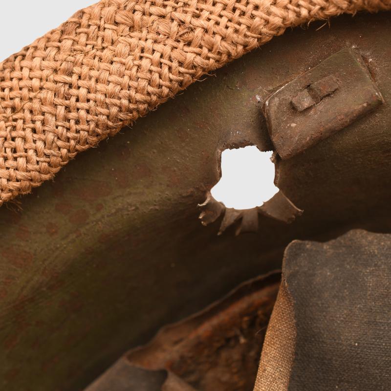 BRITISH WWI VERY FIRST PATTERN BRODIE HELMET IN GREEN WITH BATTLE DAMAGE AND FIELD COVER.