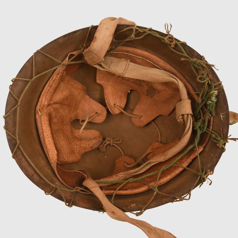 JAPANESE WWII TYPE 90 COMBAT HELMET WITH CAMOUFLAGE NET, IDENTIFIED TO AN INDIVIDUAL SOLDIER.