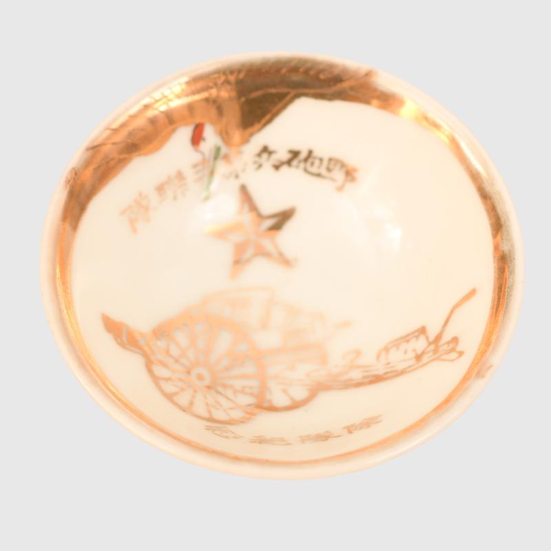 JAPANESE WWII SAKI CUP WITH IMAGES OF A FIELD GUN.